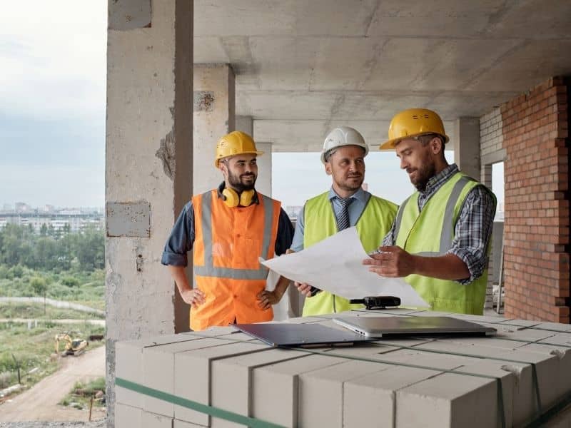 Construction professionals reviewing site plans and topographic survey information before grading and earthwork begins on a building project.