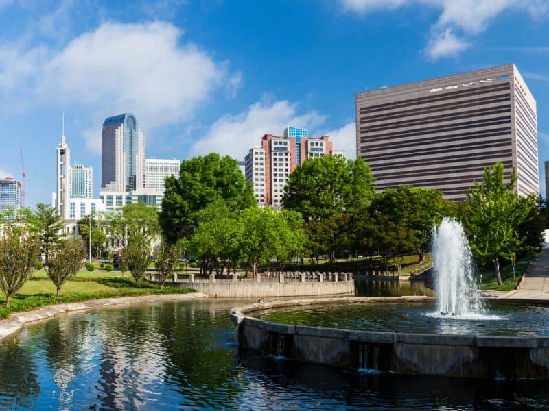 Land surveying in Charlotte North Carolina with a view of the city skyline, park fountain, and surrounding urban landscape
