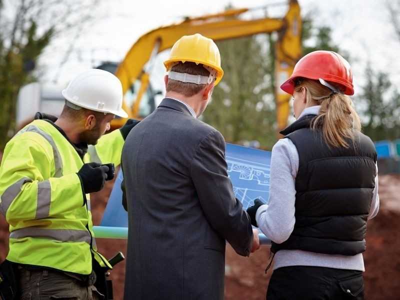Surveyor and project team reviewing site plans to guide drainage sensitive grading and layout decisions